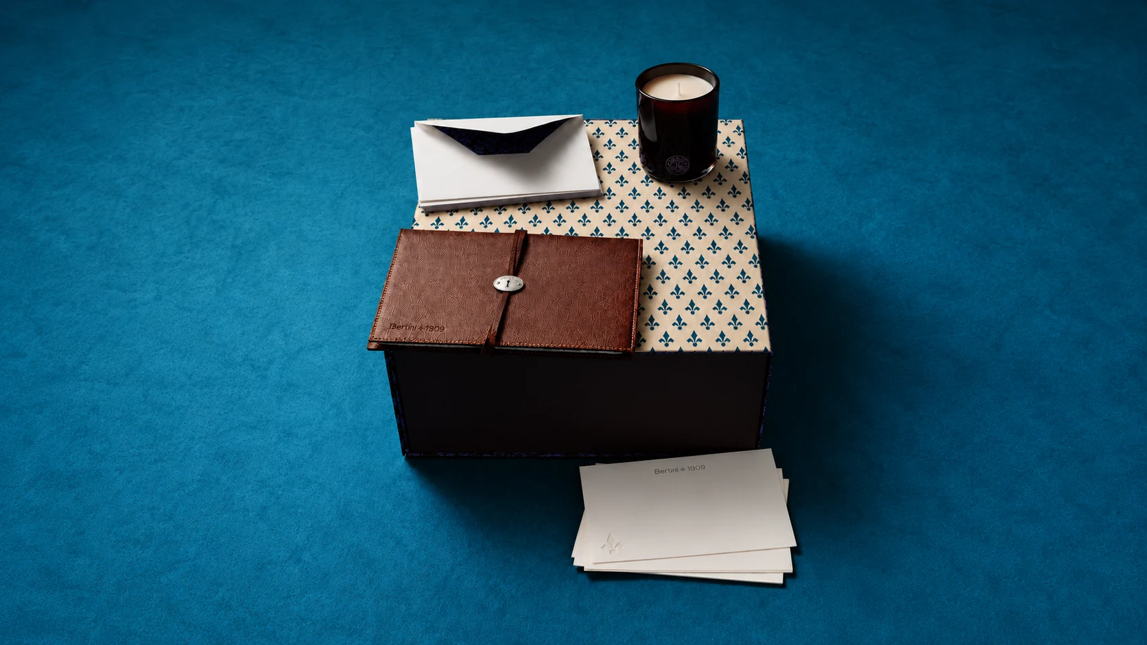 Bertini 1909 stationery and gift objects arranged on petrol-blue fabric